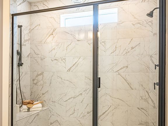 Fully tiled roman shower with bench and sleek black frame and hardware
