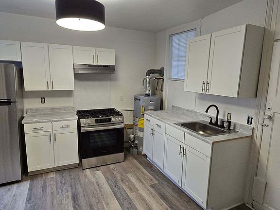 Kitchen w/ new refrigerator/freezer and stove/hood, new countertops, new sink w/ new faucet; hot water heater has been covered up