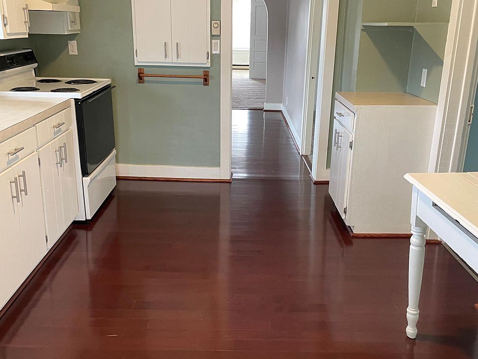 Kitchen with stove, hood and refrigerator and microwave shelf. Hard wood floors.