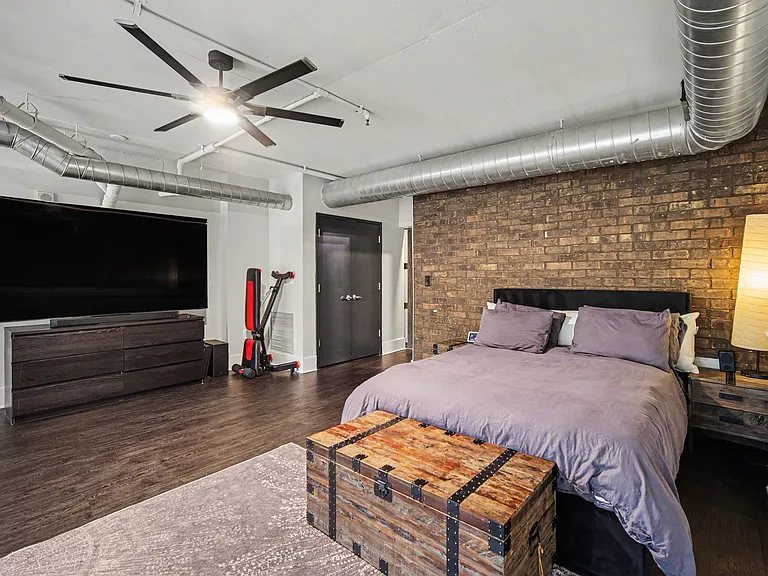 Master Bedroom with stunning brick accent wall, queen bed, 85" Samsung Smart TV, 5.1 sound system, Bowflex bench and adjustable weights up to 52.5 lbs per dumbbell, yoga matt, resistance bands and direct access to master bathroom and walk in closet