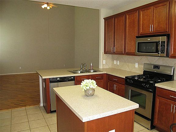 Gourmet island kitchen features beautiful Corian countertops, ceramic tile flooring & backsplash, stainless dishwasher, energy efficient gas oven/range & handy built-in microwave, abundant 42" cabinetry, & large breakfast bar!