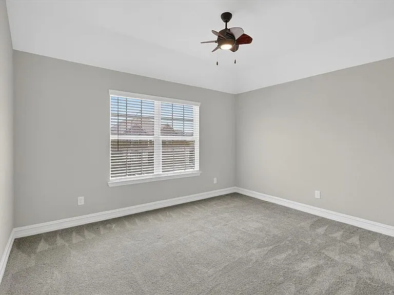 Carpeted room with a tray ceiling and a window featuring blinds