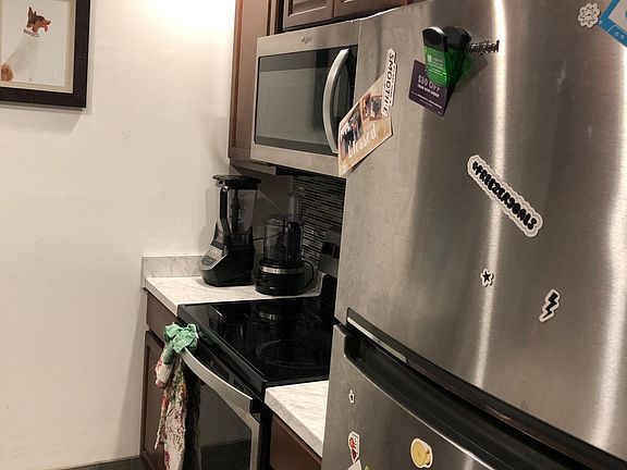 The kitchen includes new stainless appliances: refrigerator, microwave, stove, and dishwasher