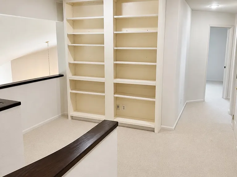 Upstairs features an open wall bookcase and a flexible area for a home office