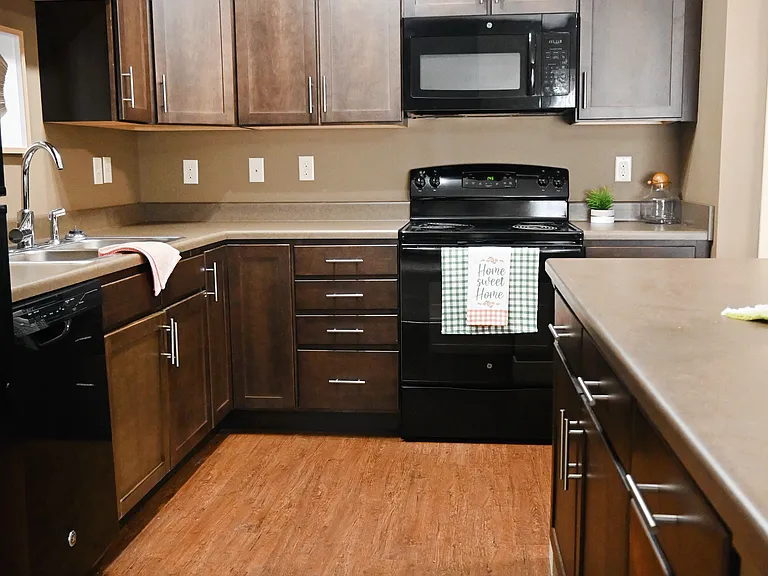 A kitchen with wooden floors and black appliances.