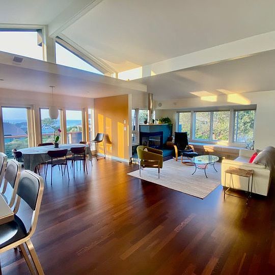 Open light filled dining and living area with vaulted ceilings and sliders onto deck