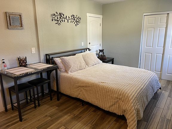 Fully furnished studio featuring a comfortable queen-size bed, durable porcelain tile flooring, and dedicated workspace area.