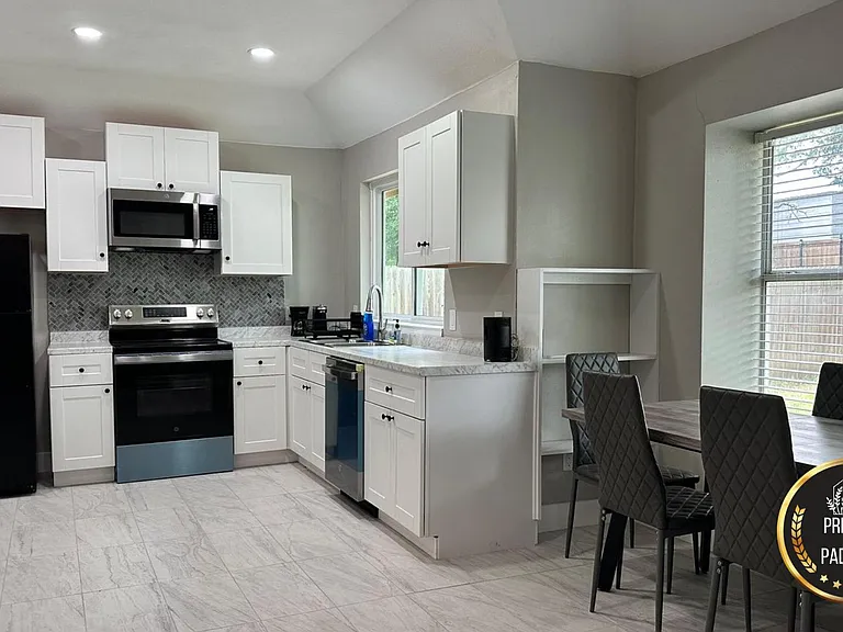 Spacious eat-in kitchen with white cabinetry, full appliance package, and a large window overlooking the yard.