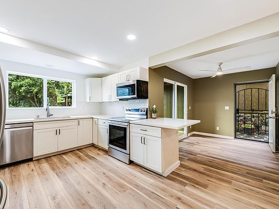 Kitchen-dining room with sliding patio doors opening to the lanai and deck, and side garden nook.
