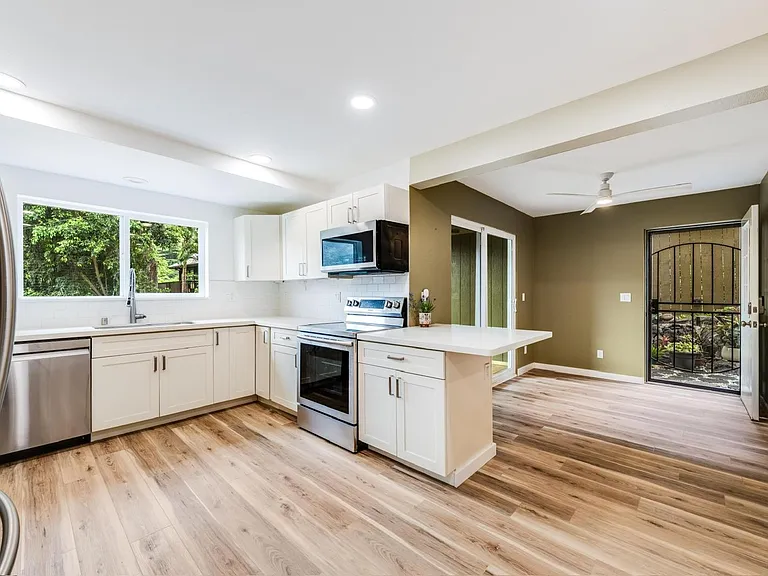 Kitchen-dining room with sliding patio doors opening to the lanai and deck, and side garden nook.