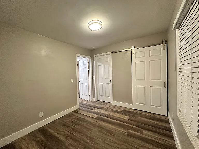 Bedroom. Open doorway on far left goes out to living room. Door in middle goes to laundry / furnace room. Sliding door on right is closet.