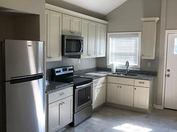 Kitchen with cathedral ceiling, new appliances, granite countertops and backdoor that leads out to spacious deck.