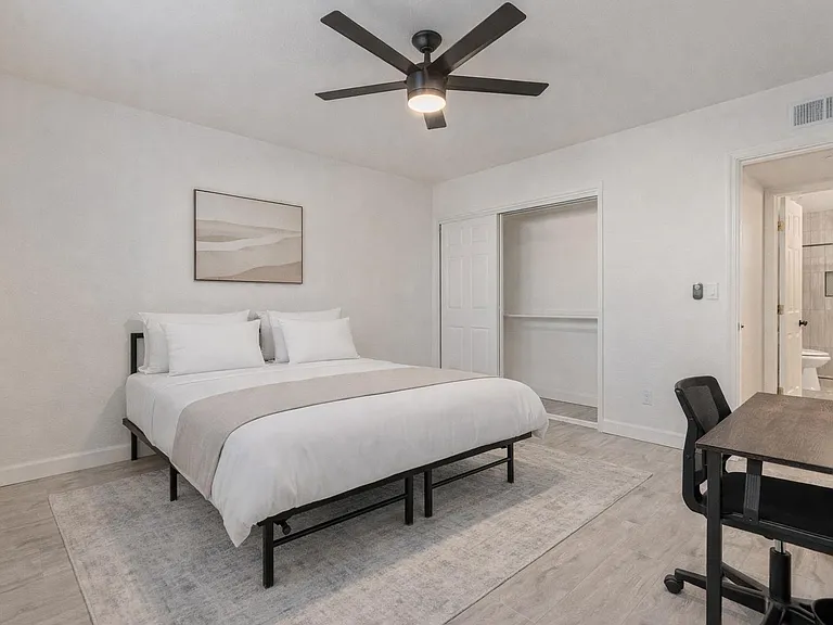 Queen Size bed with private bath, desk, chair, lamp, fan. Bedding and rug virtually staged.
