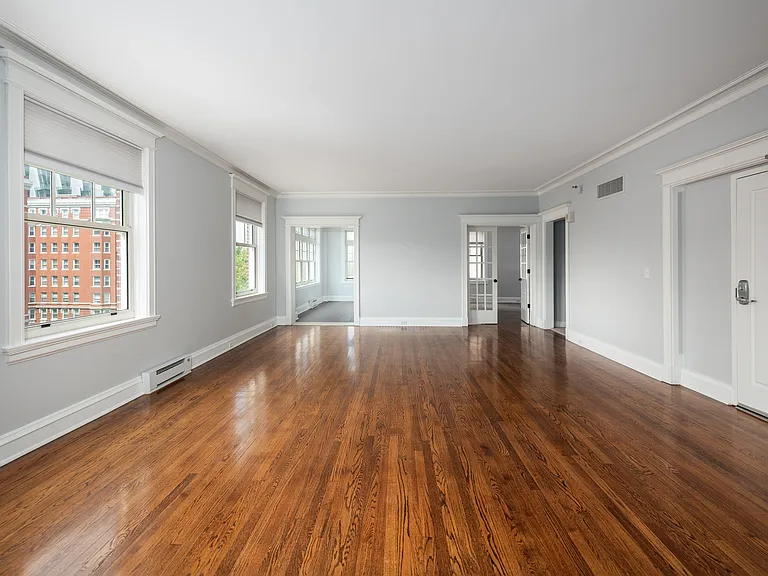 York House large living room with oak hardwood flooring, crown molding and french doors.