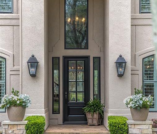 An impressive entrance is accented by two gas lanterns and an iron door complemented by professional landscape design.
