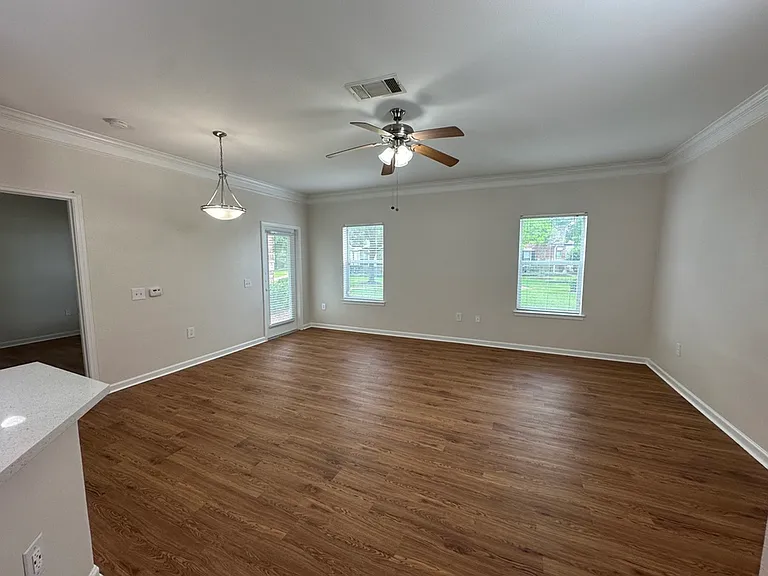 Spacious living area with elegant wood-style floors, large windows, and modern lighting in an inviting open-concept layout. Spacious living area with elegant wood-style floors, large windows, and modern lighting in an inviting open-concept layout.