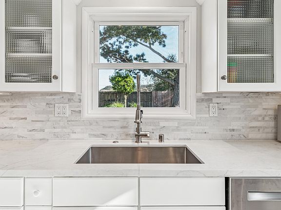 quartz countertops, stylish backsplash and a window inviting the natural setting in.