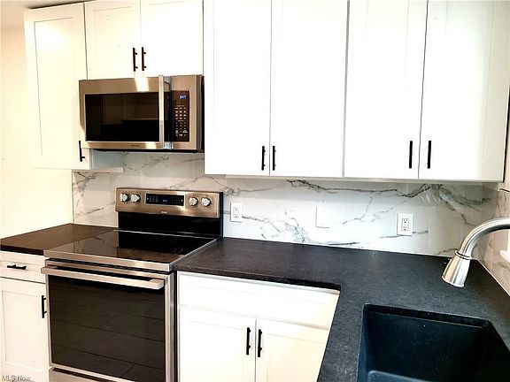 High-end brand-new appliances including microwave, stove, refrigerator, and dishwasher.