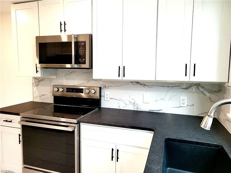High-end brand-new appliances including microwave, stove, refrigerator, and dishwasher.