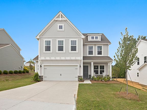 A large white house with a gray roof and a large driveway.