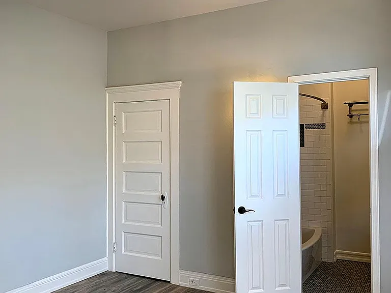 View of the bedroom with new hardwood flooring and lighting, fresh paint, closet and renovated bathroom.