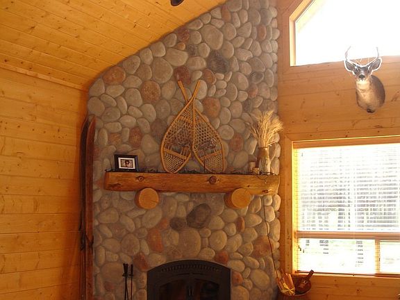 Floor to ceiling river-rock fireplace in living area w/knotty pine millwork.