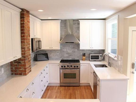 Gas stove situated among Italian marble backsplash. Tall cabinets for lots of storage.