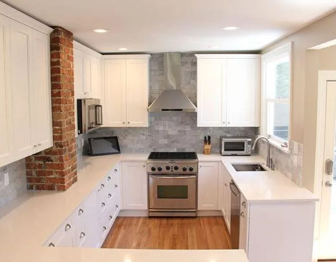 Gas stove situated among Italian marble backsplash. Tall cabinets for lots of storage.