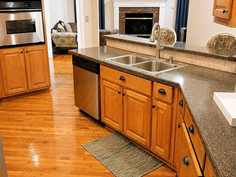 Spacious kitchen with granite counters, double-basin sink, ample cabinetry, and stainless built-ins, opening to a fireplace l