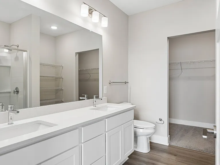 Bathroom with quartz countertops, closet, and bath/shower of an apartment unit.