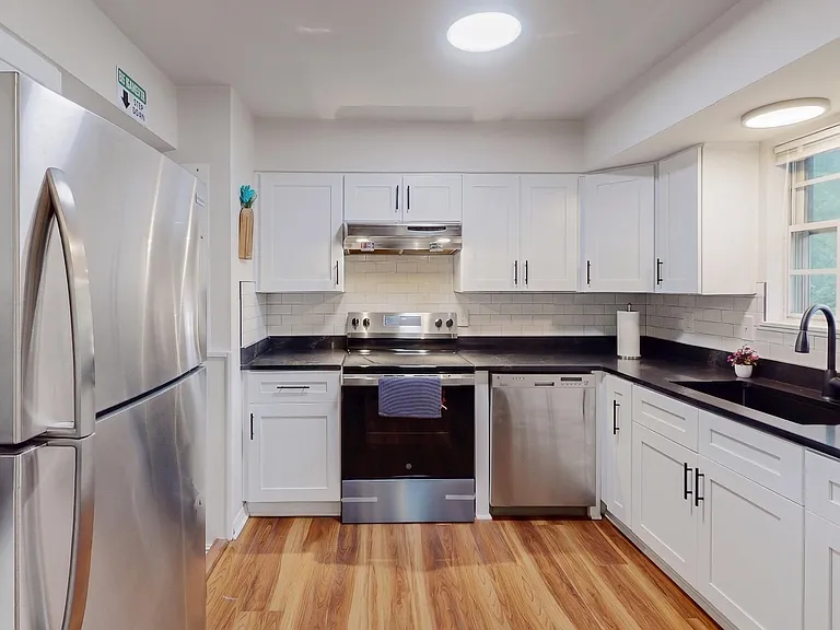 Updated kitchen with stainless steel appliances, ample white cabinetry, subway-tile backsplash, and generous counter space.
