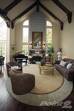 Soaring 25' ceilings in this elegant and comfortable family room! Features include many windows for natural light, neutral decor, hardwood floors, wood burning fireplace with tall mantel and beautiful, contrasting wood beams on the cathedral ceilings.