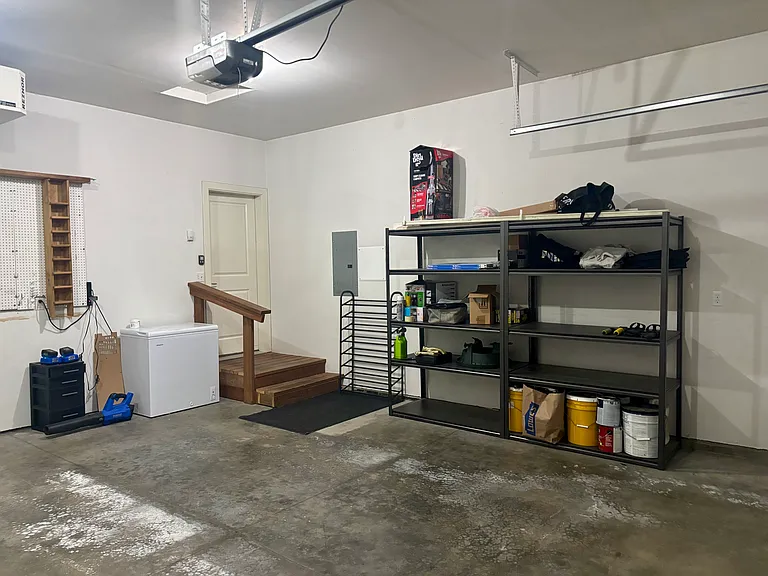 Two-car garage supplies all garden and snow tools, snowblower, mower, shelving for storage and a small freezer