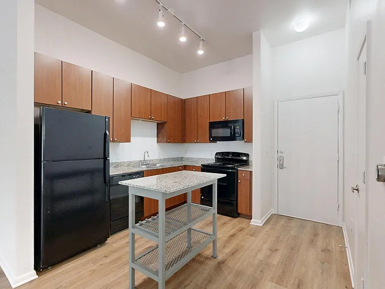 Apartment kitchen with stone counters and wood style floor.