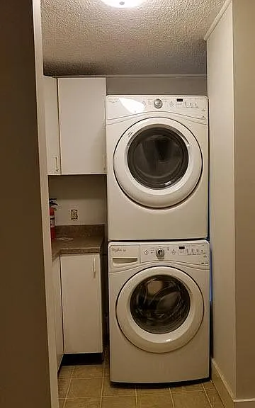 laundry area with cabinet storage - stackable washer/dryer stays.