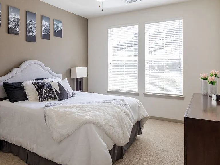 Centro Apartments model bedroom with 2 windows and white comforter
