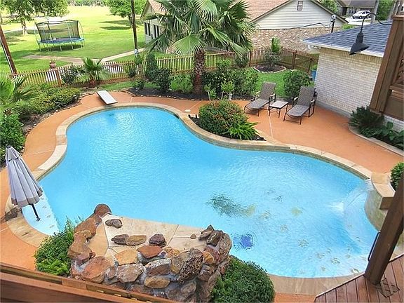 View of the pool from the master suite. Relax under the umbrella with a cool drink. Fully landscaped