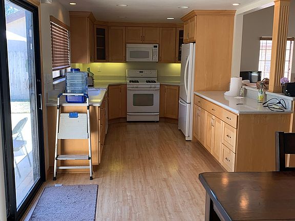 Kitchen- solid surface countertops & newer cabinets with bar countertop open to living room.