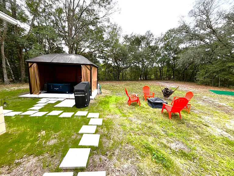 Firepit, gas grill and screened gazebo with seating and inflatable hot tub.