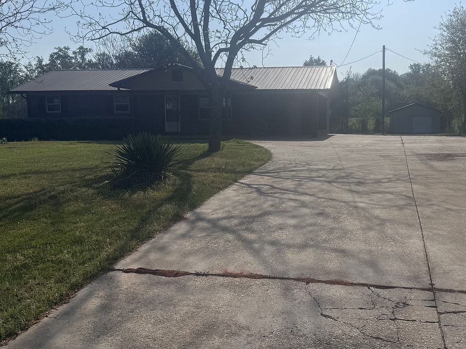 Concrete driveway with carport and storge building in backyard.