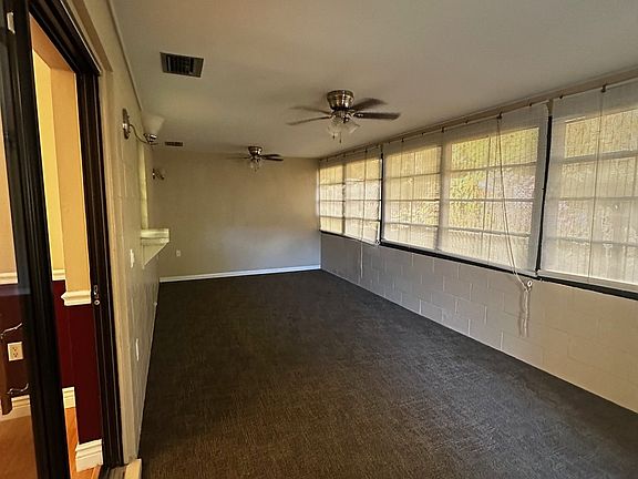 Spacious climate-controlled Florida room featuring wall-to-wall windows for abundant natural light, ceiling fans, and durable flooring. Comfortable year-round and ideal as a bonus living space.