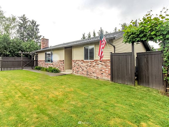 Fully fenced front yard has a walk thru gate framed with grapes. Plenty of room for parking a trailer or toys. Pull them thru the open side of the garage. 