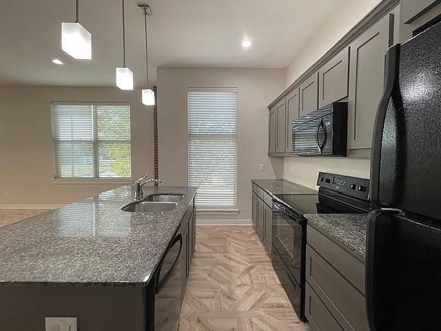 Kitchen featuring black appliances, hanging light fixtures, gray cabinetry, dark stone counters, and recessed lighting