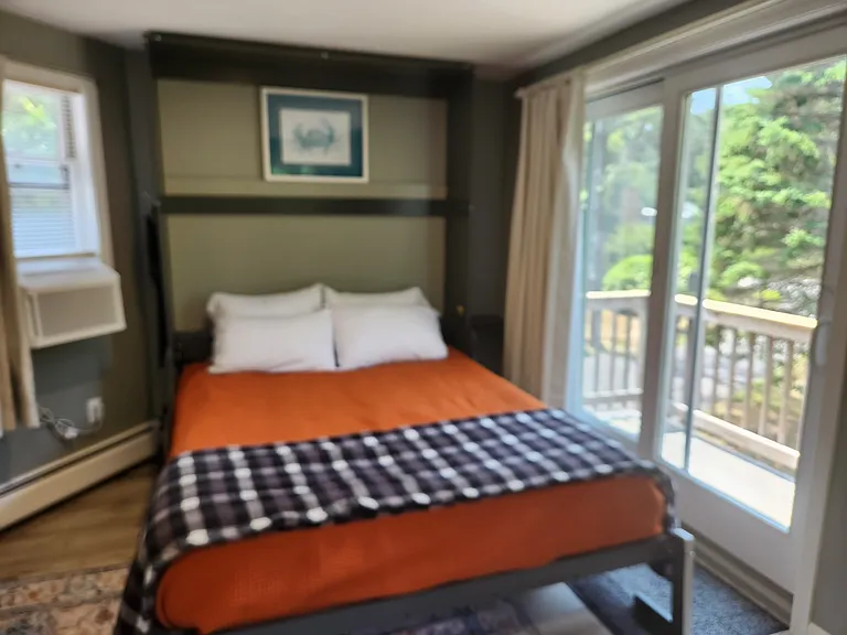 Bedroom 3 with queen bed on second floor, separate entrance, mini-fridge, mircowave, smart TV, fold away table and chairs, shower stall, bathroom sink, toilet, and views of backyard.