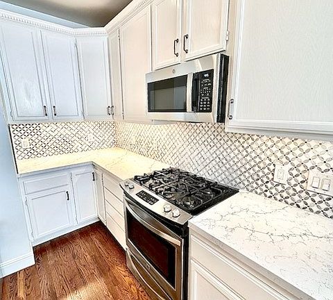 Unit #504 stunning chefs kitchen with marble countertops custom backsplash and stainless steel appliances including gas stove!