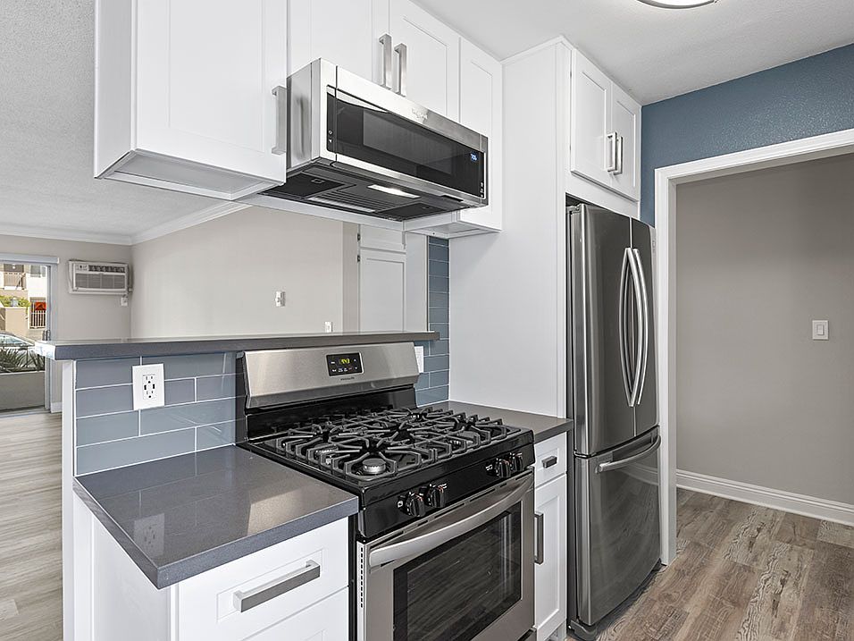 Kitchen with blue tile backsplash and stainless steel Stove, Oven, and fixtures.