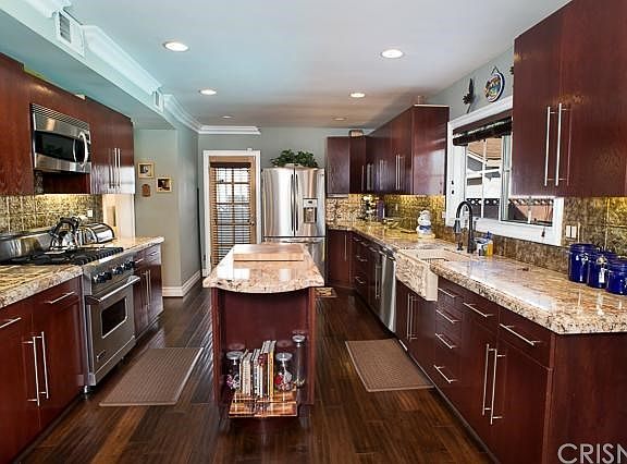 The gorgeous kitchen features granite counter tops & custom back splash, rich wood cabinetry, center island, Viking range/oven, stainless steel appliances, recessed lighting, crown moldings, under cabinet lighting, and rich wood floors.