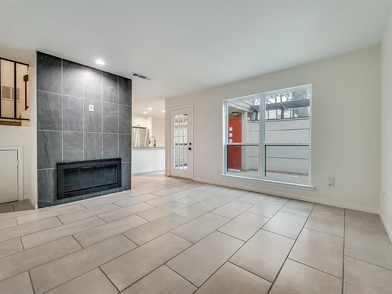 Living area with large format tile flooring, a dark tile fireplace surround, and a built-in electric fireplace