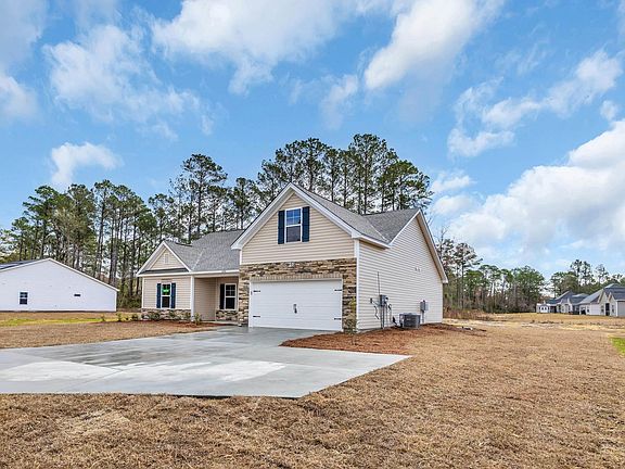 Traditional-style house featuring central air condition unit, an attached garage, stone siding, and