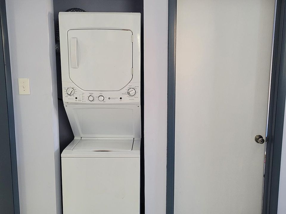 In unit washer/dryer combo in the Kitchen. To the right is the door to the second bedroom.